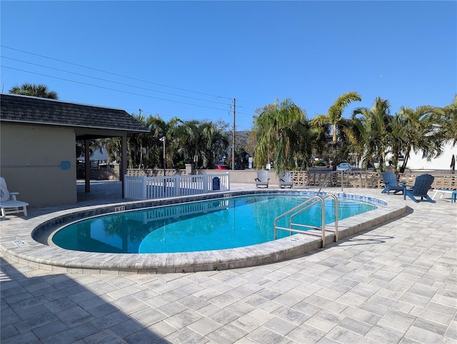 community pool with a patio area and fence