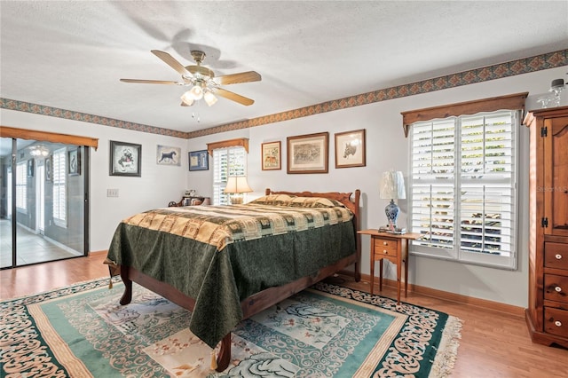 bedroom featuring access to exterior, a textured ceiling, light hardwood / wood-style floors, and ceiling fan