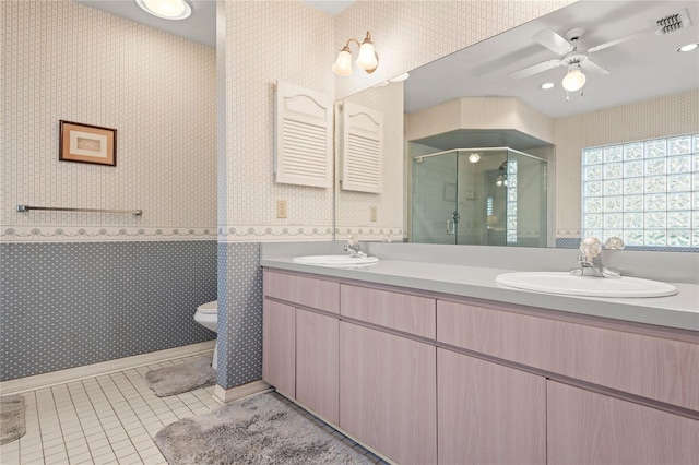 bathroom featuring ceiling fan, tile patterned flooring, toilet, vanity, and a shower with shower door