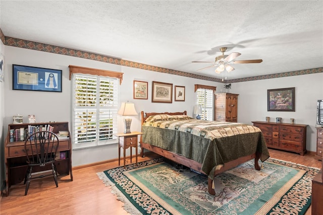 bedroom with ceiling fan, light hardwood / wood-style floors, and a textured ceiling