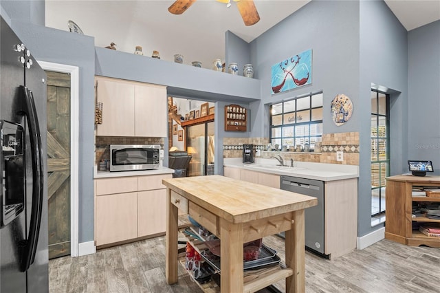 kitchen with light hardwood / wood-style floors, a high ceiling, and appliances with stainless steel finishes