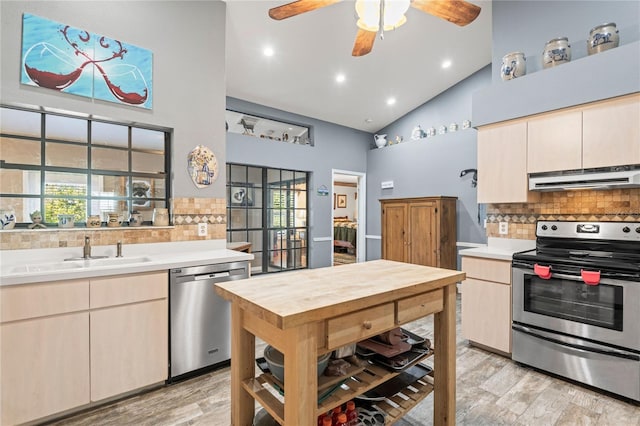 kitchen with backsplash, high vaulted ceiling, sink, light wood-type flooring, and stainless steel appliances