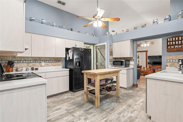 kitchen featuring light hardwood / wood-style floors, black fridge, white cabinetry, and sink