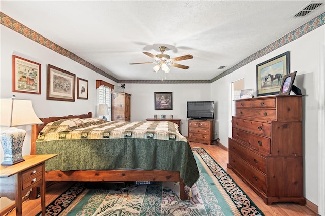 bedroom with hardwood / wood-style floors, a textured ceiling, and ceiling fan