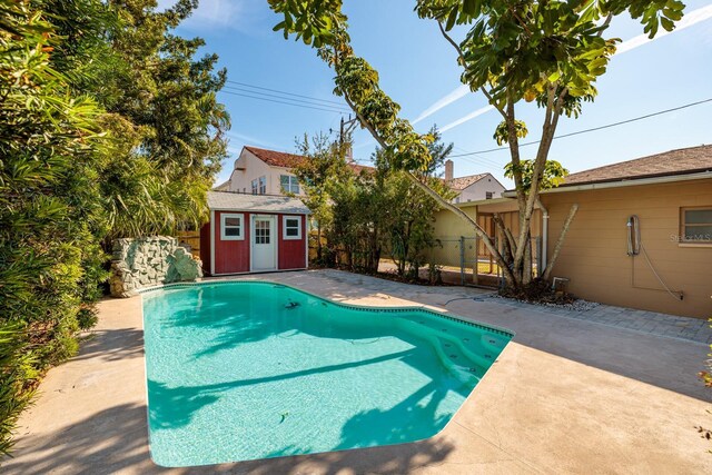 view of pool featuring a patio and a storage shed