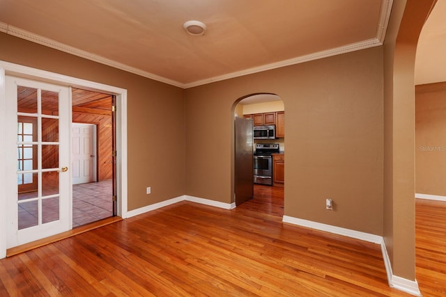 spare room with light wood-type flooring, crown molding, and french doors