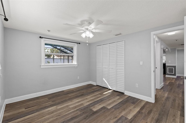 unfurnished bedroom featuring a textured ceiling, ceiling fan, dark wood-type flooring, and a closet