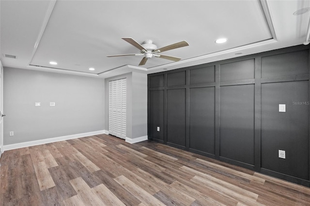 unfurnished bedroom featuring light wood-type flooring, a tray ceiling, and ceiling fan