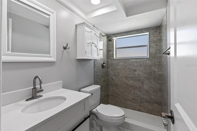 bathroom with vanity, toilet, and tiled shower