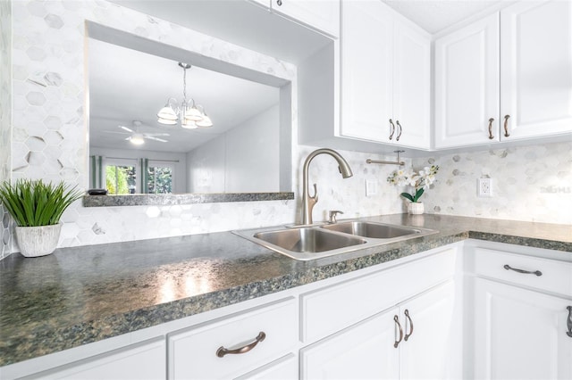 kitchen with white cabinets, ceiling fan with notable chandelier, tasteful backsplash, and sink