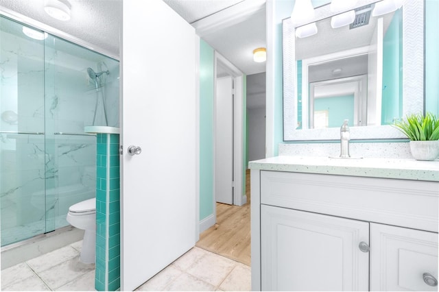 bathroom featuring a textured ceiling, toilet, wood-type flooring, and walk in shower