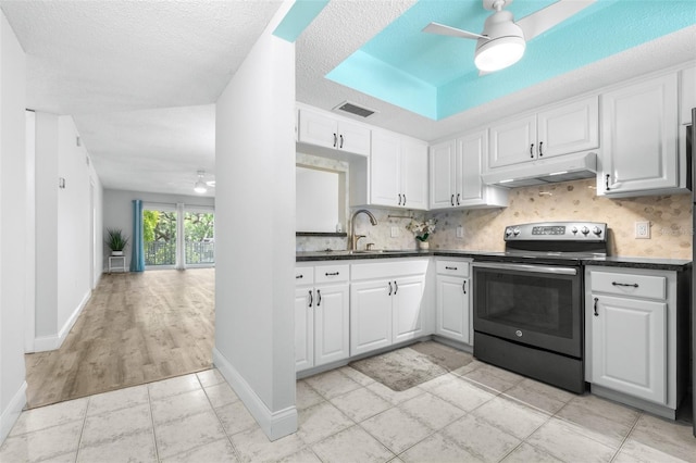 820 Patricia Ave Unit 207, Dunedin, FL 34698 - kitchen featuring stainless steel range with electric stovetop, a ceiling fan, under cabinet range hood, dark countertops, and a sink