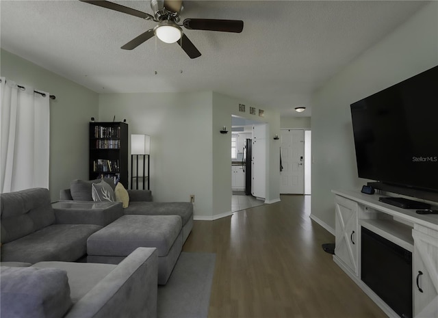 living room featuring ceiling fan, a textured ceiling, and light hardwood / wood-style flooring