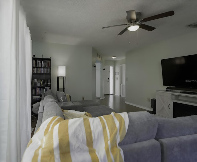 living room with ceiling fan and a textured ceiling