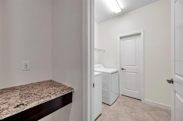 laundry room featuring washer and clothes dryer, light tile patterned flooring, and a textured ceiling