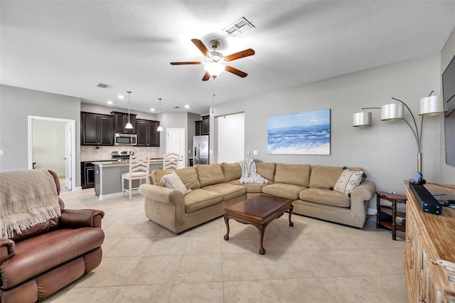 tiled living room featuring ceiling fan and a textured ceiling