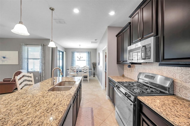 kitchen with sink, light stone counters, decorative light fixtures, decorative backsplash, and appliances with stainless steel finishes