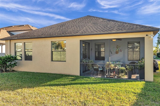 rear view of house with a sunroom, ceiling fan, and a yard