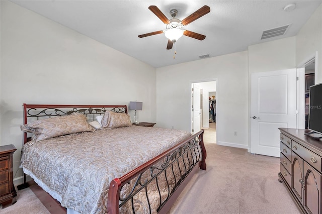 carpeted bedroom with a walk in closet and ceiling fan