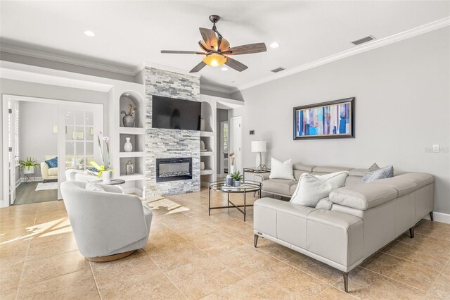 living room featuring ceiling fan, a healthy amount of sunlight, a stone fireplace, built in features, and crown molding