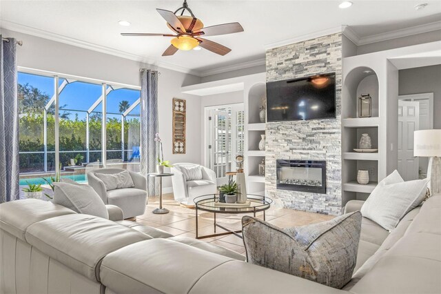 living room featuring a fireplace, built in features, ceiling fan, and crown molding