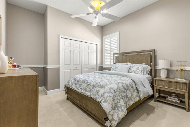 bedroom with ceiling fan, light carpet, and a closet