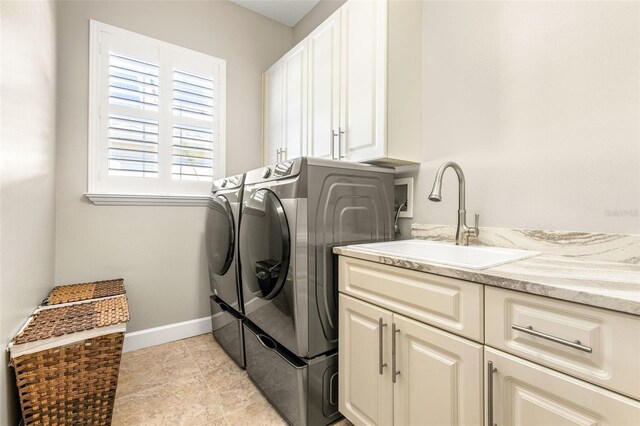 clothes washing area with cabinets, separate washer and dryer, and sink