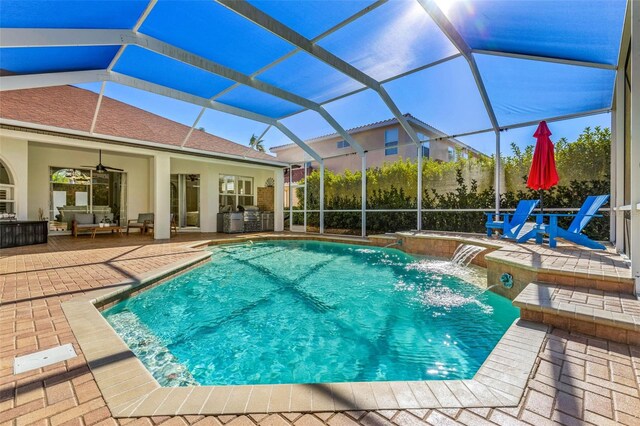 view of swimming pool with an outdoor kitchen, pool water feature, ceiling fan, a lanai, and a patio