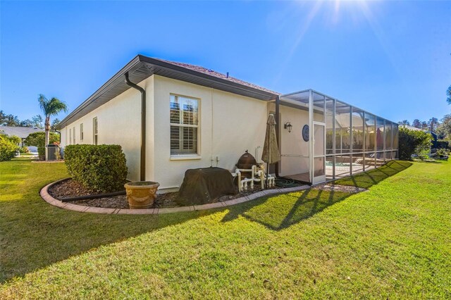 back of property featuring a lawn and glass enclosure