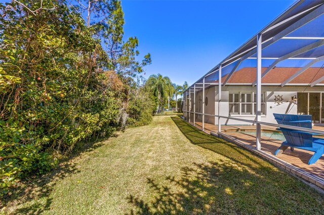 view of yard featuring glass enclosure, a swimming pool, and a patio