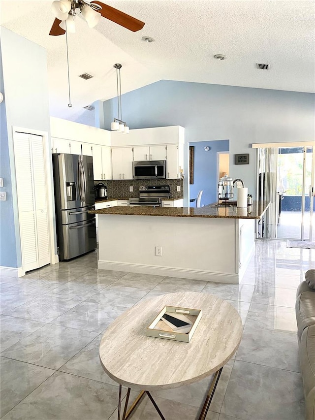 kitchen with high vaulted ceiling, stainless steel appliances, visible vents, white cabinets, and backsplash