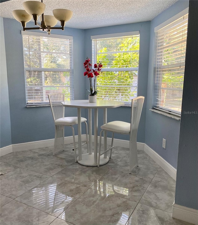 dining area featuring a notable chandelier, a textured ceiling, and baseboards