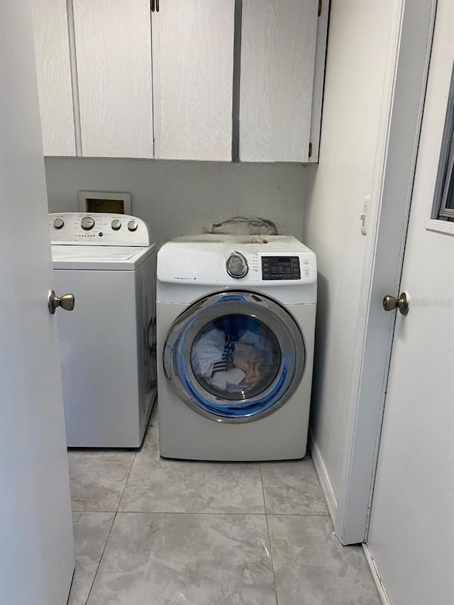 laundry area with washing machine and clothes dryer, cabinet space, and baseboards