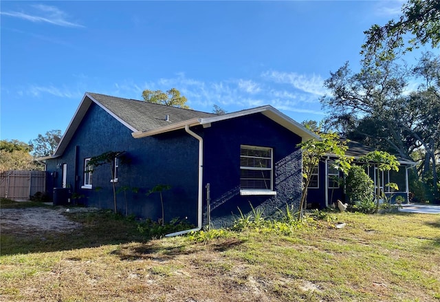 view of side of property with cooling unit, fence, and stucco siding