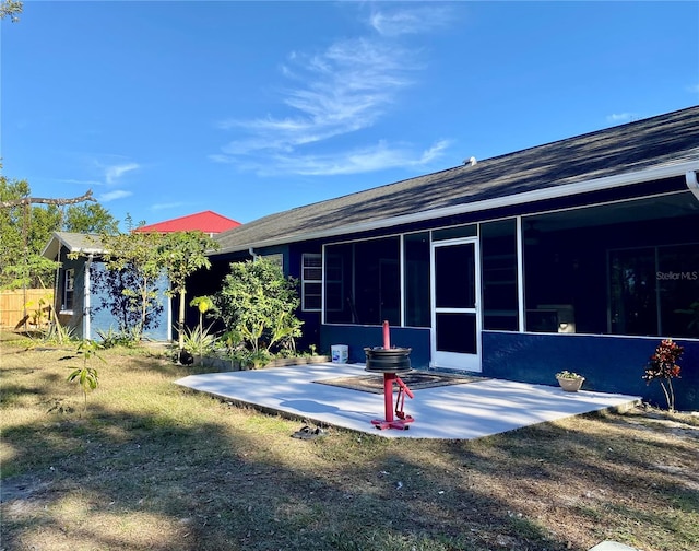 rear view of property with a sunroom, a yard, and a patio