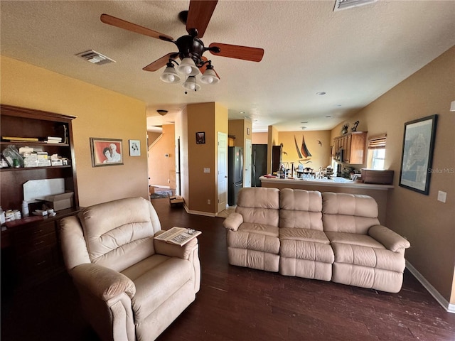 living room with ceiling fan, dark wood-type flooring, and a textured ceiling