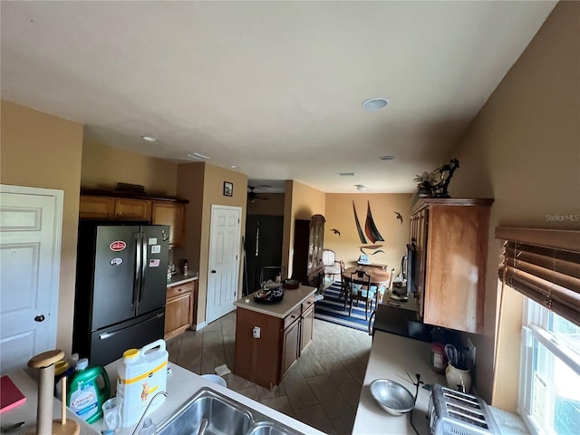 13404 Hampton Park Ct, Fort Myers, FL 33913 - kitchen with freestanding refrigerator, a center island, light countertops, ceiling fan, and brown cabinetry