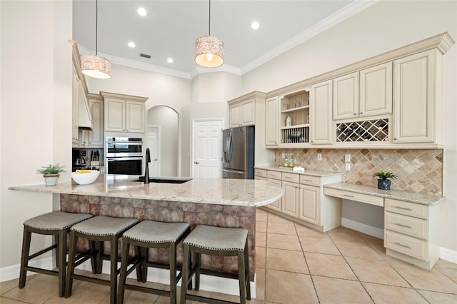 kitchen featuring decorative light fixtures, sink, light stone counters, and stainless steel appliances