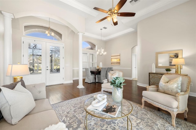 living room featuring ceiling fan with notable chandelier, ornate columns, dark wood-type flooring, and french doors