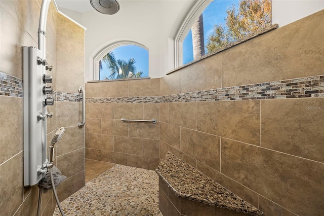 bathroom featuring tiled shower and tile walls