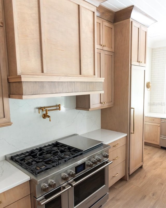 kitchen featuring decorative backsplash, light brown cabinetry, stainless steel appliances, and light hardwood / wood-style floors