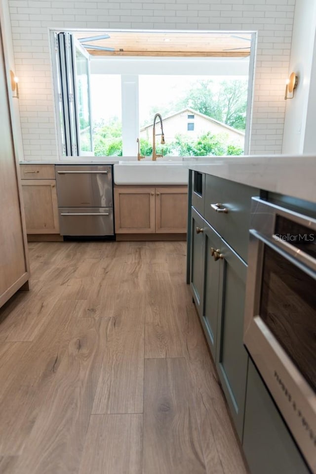 kitchen with appliances with stainless steel finishes, light hardwood / wood-style floors, sink, and light brown cabinets