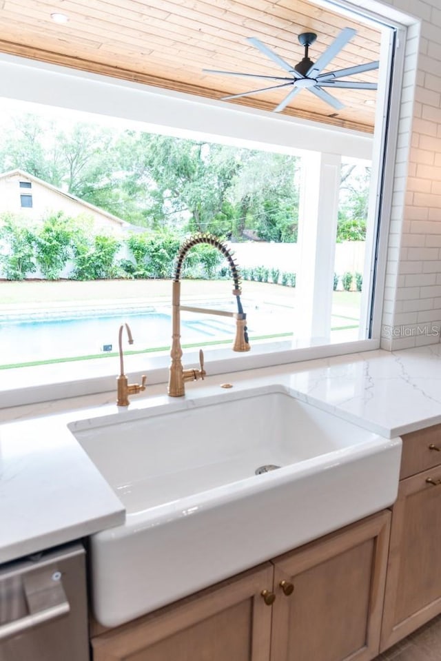 interior details with ceiling fan, sink, light stone countertops, and stainless steel dishwasher