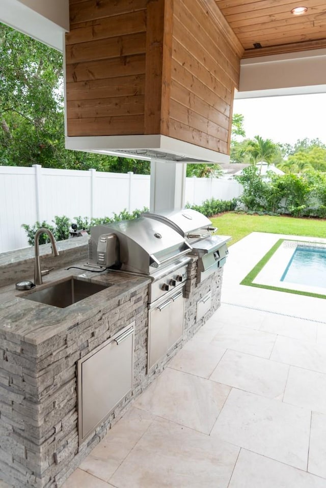 view of patio with area for grilling, a fenced in pool, and sink