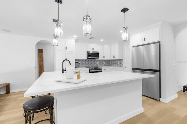 kitchen with light wood-type flooring, stainless steel appliances, white cabinetry, and a large island