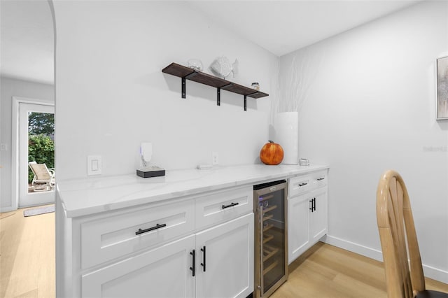 bar featuring light hardwood / wood-style floors, light stone counters, white cabinetry, and wine cooler