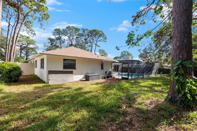 back of property featuring glass enclosure, a fenced in pool, and a yard