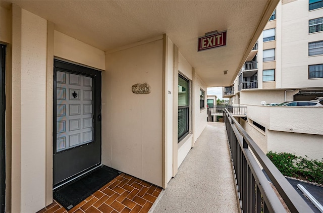 view of exterior entry with a balcony and stucco siding