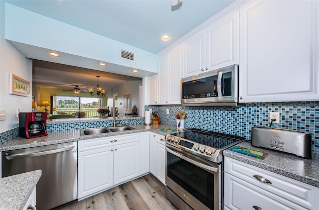 kitchen with backsplash, stainless steel appliances, white cabinetry, and sink