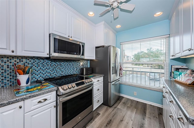 kitchen with appliances with stainless steel finishes, light wood-type flooring, backsplash, ceiling fan, and white cabinetry